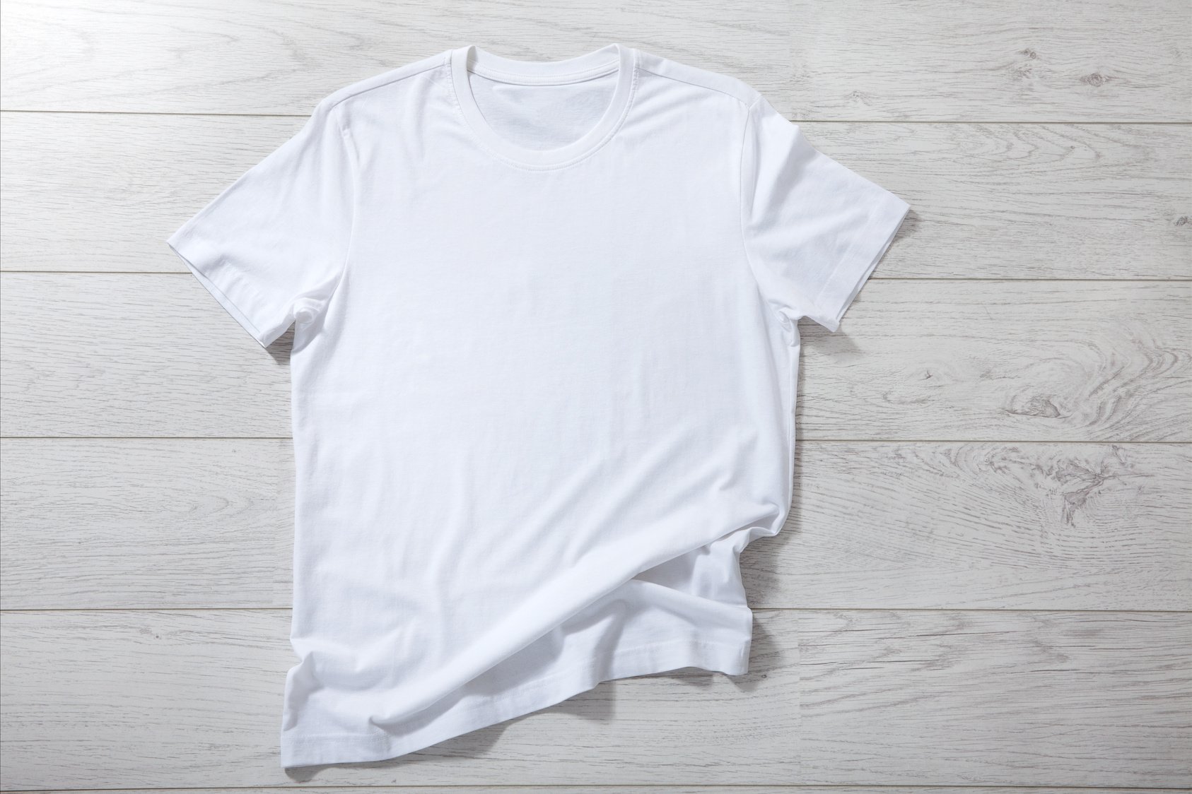 White shirt mockup isolated - pleated, wrinkled t-shirt on white background top view