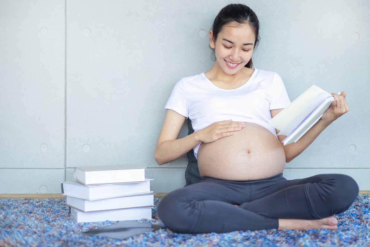 Pregnant reading a book. Pregnant woman reading a book on the sofa in the living room.